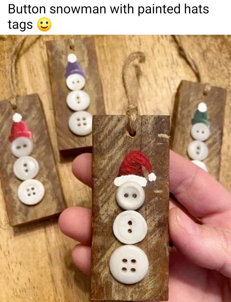 three snowman buttons are attached to wooden tags with santa's hats on them