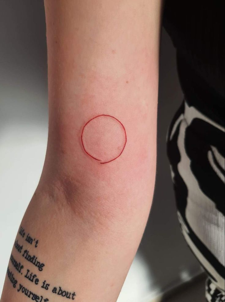 a person with a red circle tattoo on their arm