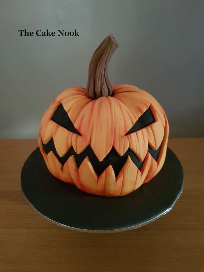 a carved pumpkin sitting on top of a black cake plate with the words, the cake nook