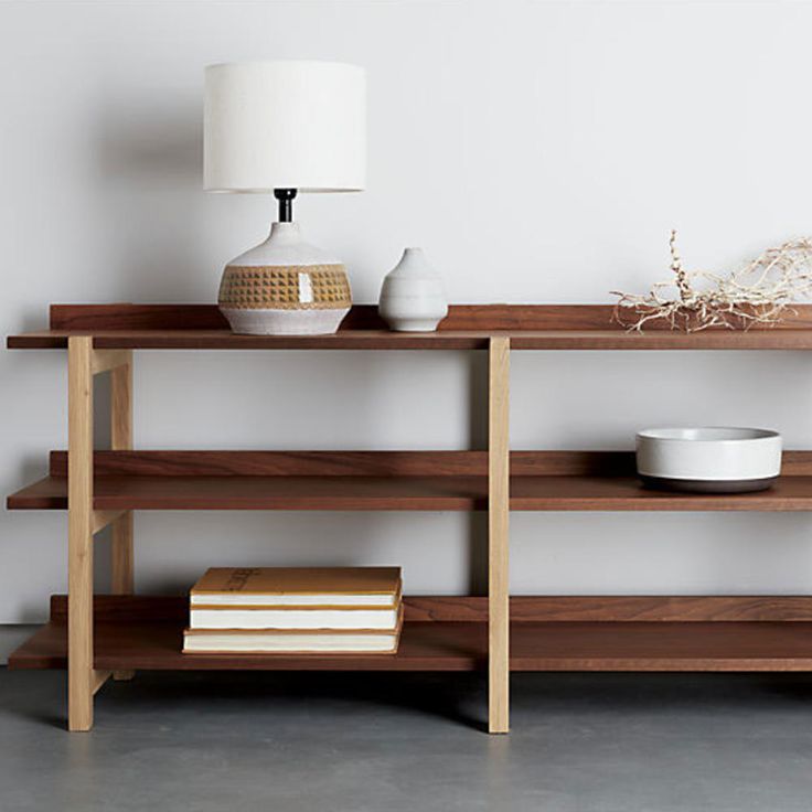 a wooden shelf with two white bowls and a lamp on the table next to it