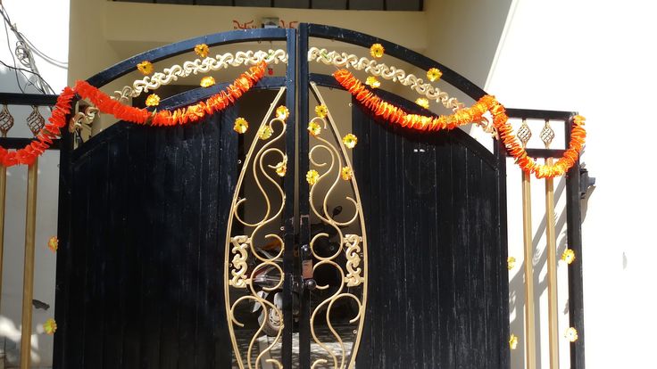 an ornate iron gate decorated with orange garlands and beads on the front entrance to a home