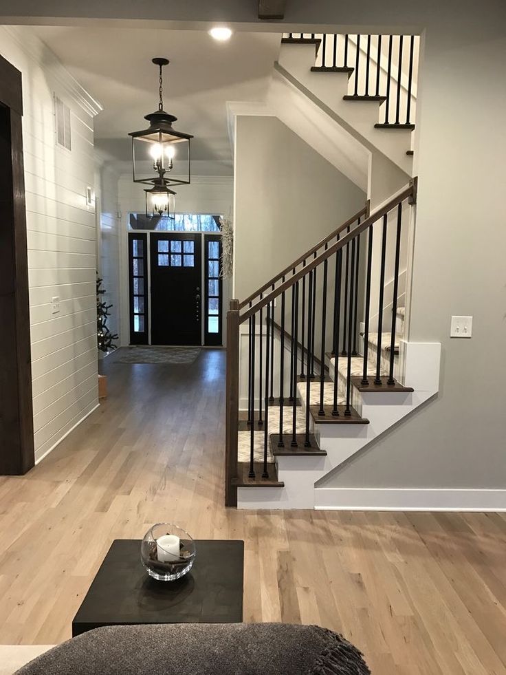 a living room filled with furniture and a stair case next to a door on the wall