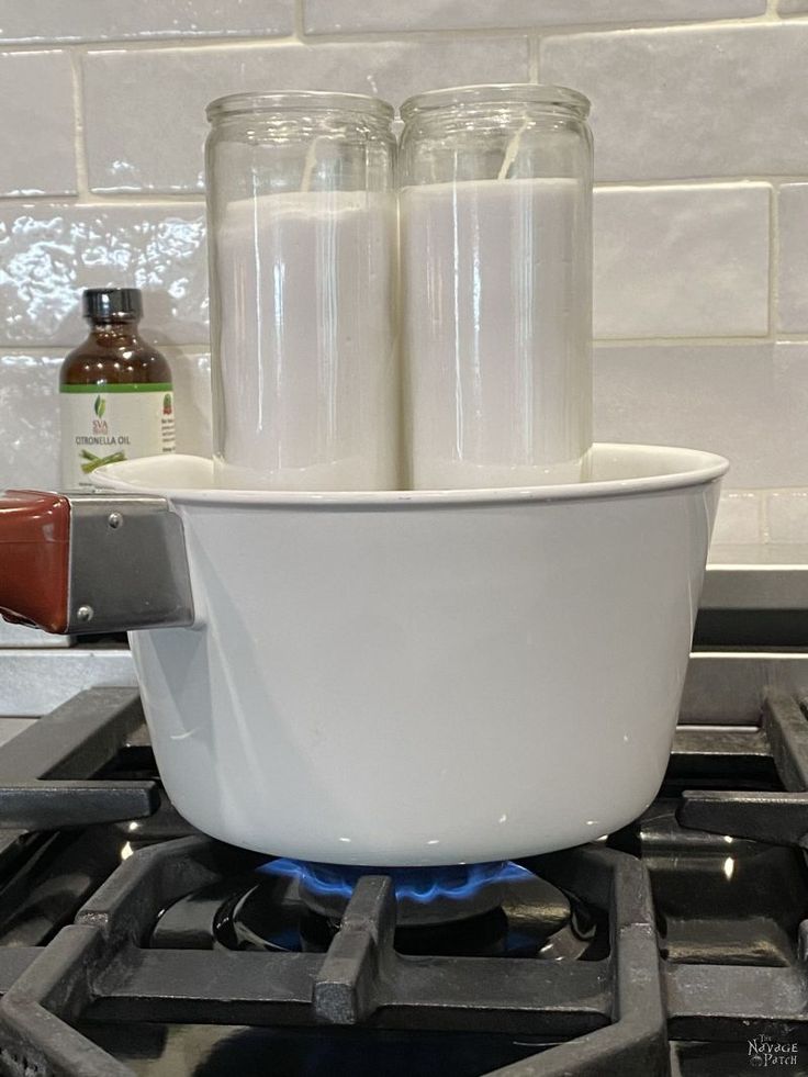 two jars sitting on top of a stove next to a bowl with liquid in it