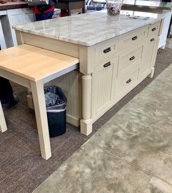 a kitchen island with two stools and a trash can in the corner next to it