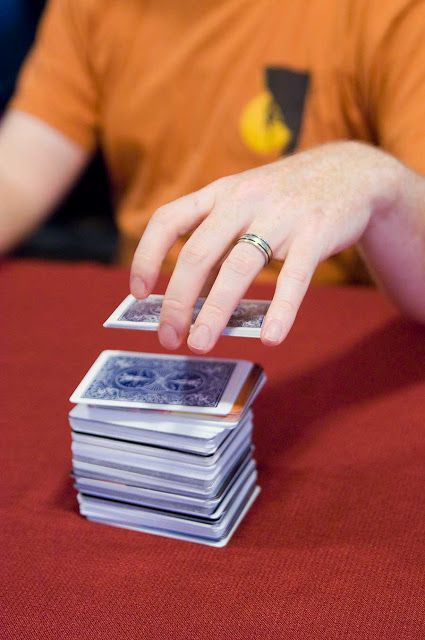 a man is stacking up playing cards with his hand on top of each other