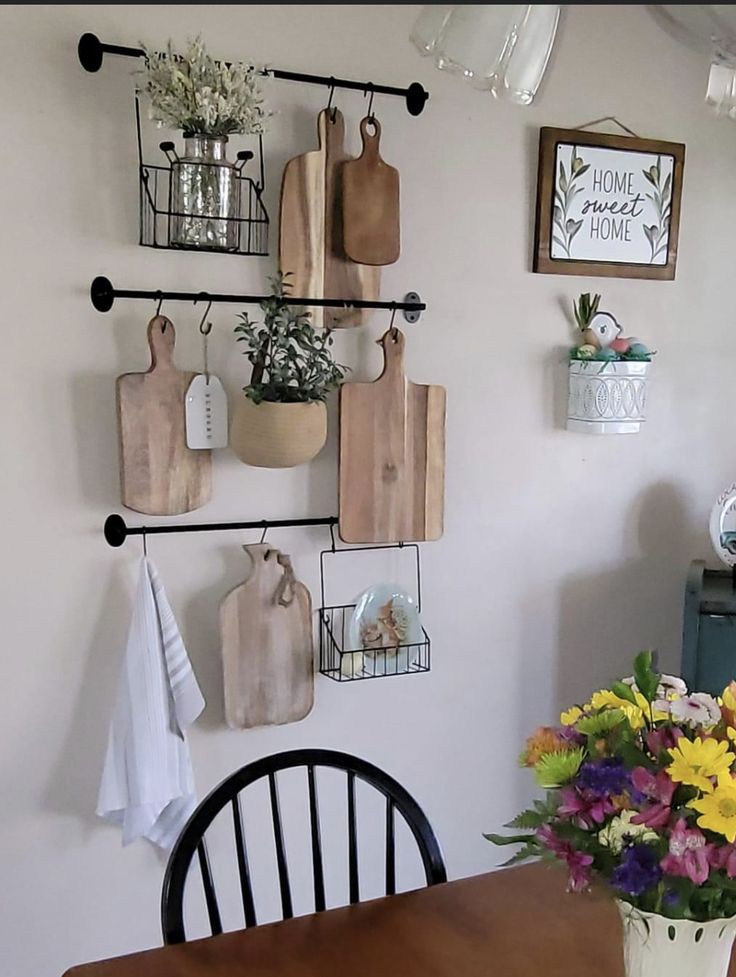 a wooden table topped with a vase filled with flowers and cutting board mounted to the wall