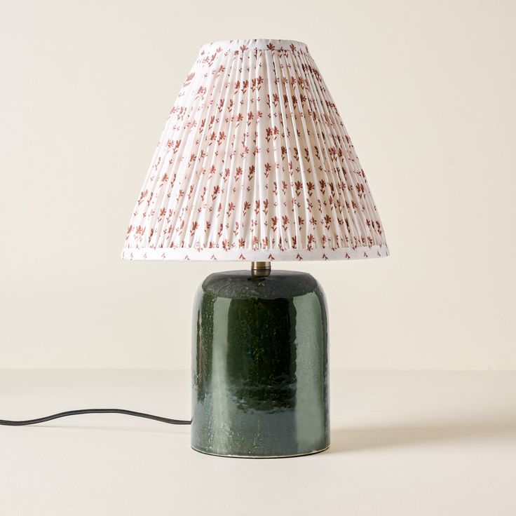 a green table lamp sitting on top of a white counter next to a light bulb