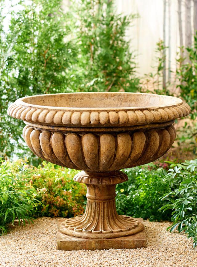 an outdoor fountain surrounded by plants and gravel