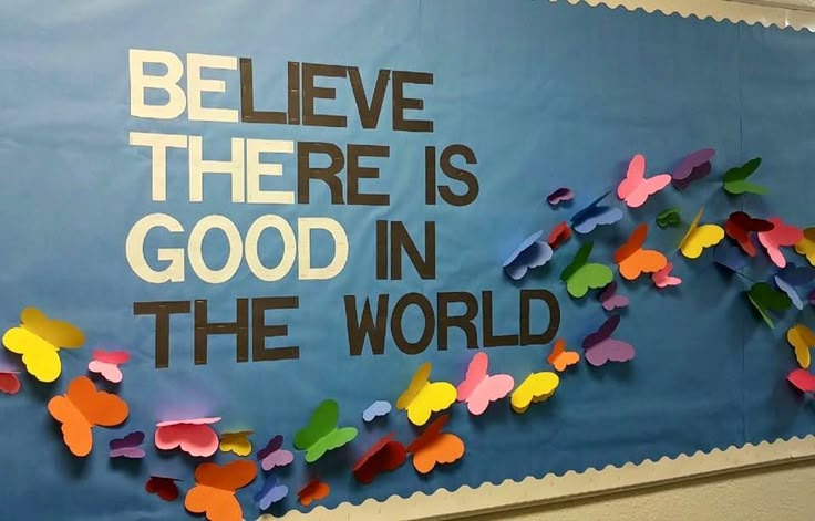 a bulletin board with colorful paper butterflies on it that says believe there is good in the world