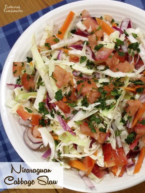 a white bowl filled with salad on top of a blue and white checkered table cloth