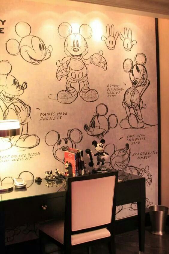 a desk with a chair and mickey mouse wallpaper on the wall in a room