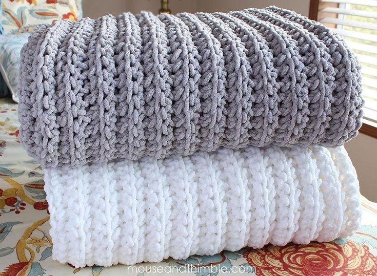 two gray and white blankets stacked on top of each other