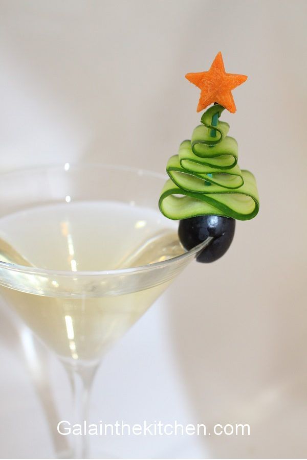 a christmas tree shaped drink in a martini glass with an olive and cucumber decoration