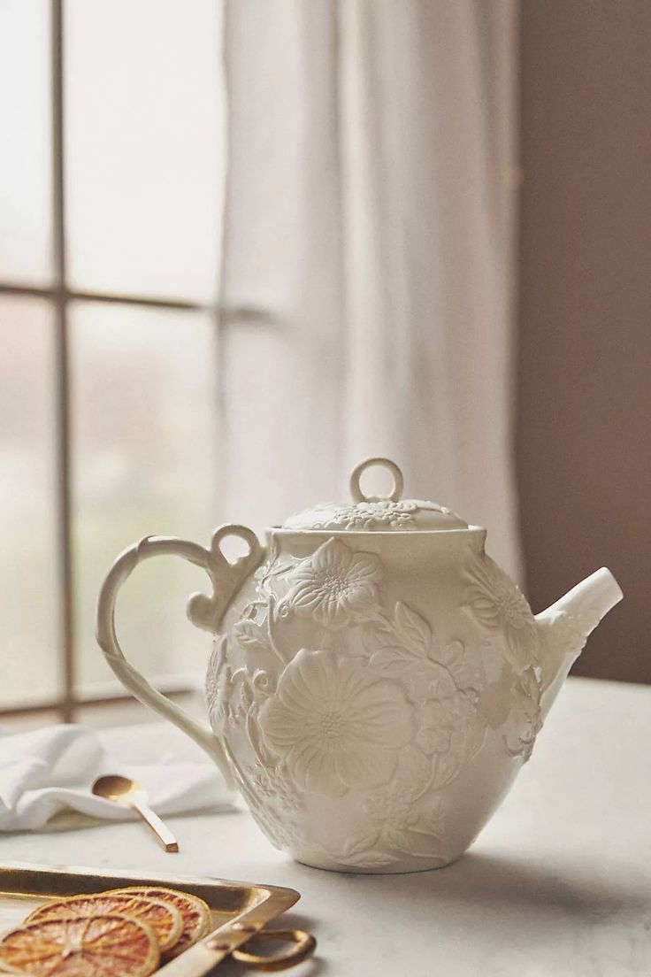 a white teapot sitting on top of a table next to scissors and other items