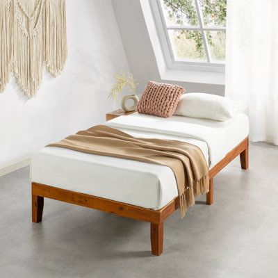 a bed sitting under a window next to a wooden frame and white sheets on top of it