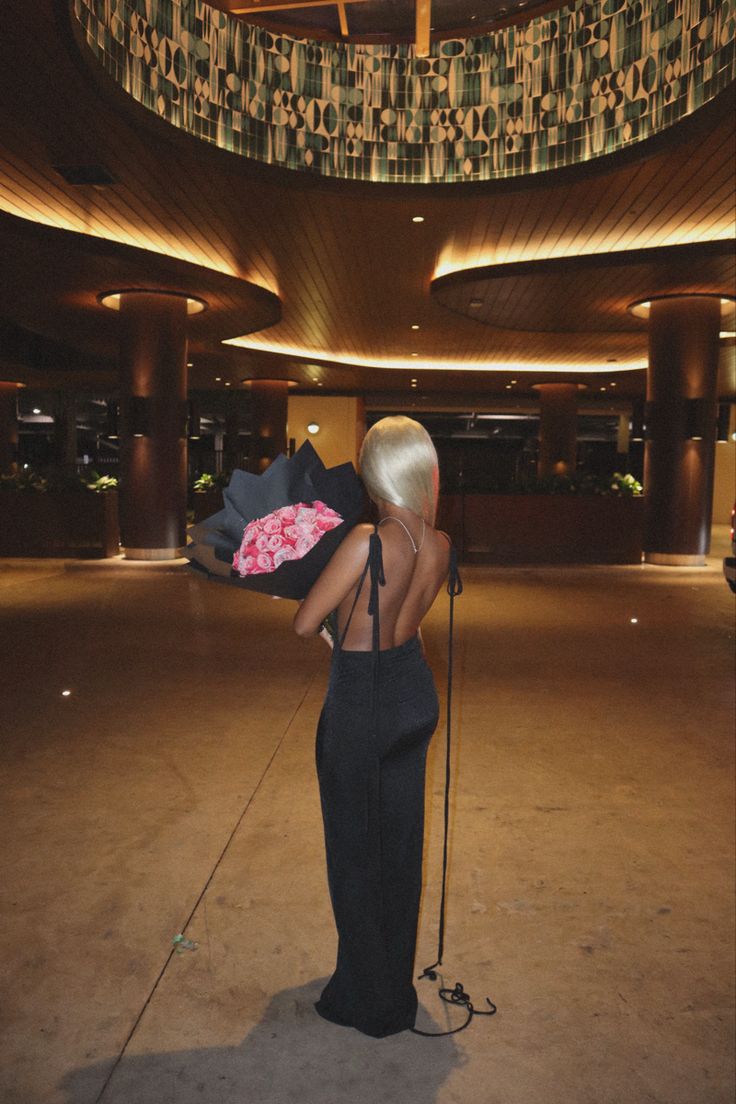 a woman with blonde hair is standing in an empty room holding a microphone and looking at the ceiling