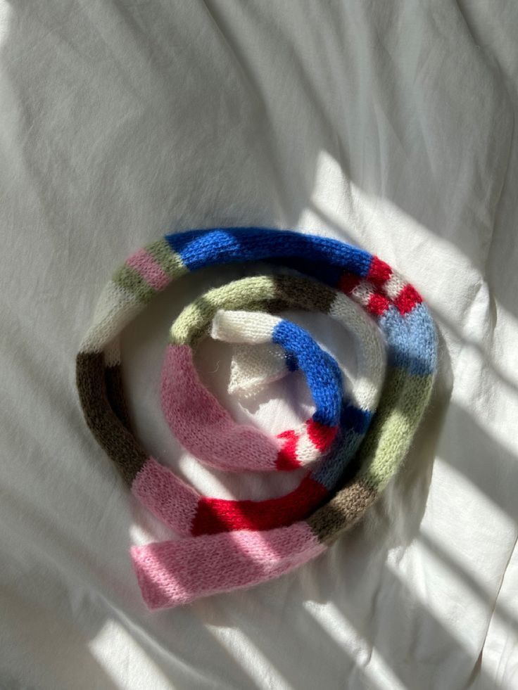 three knitted bracelets sitting on top of a white sheet covered in sun light