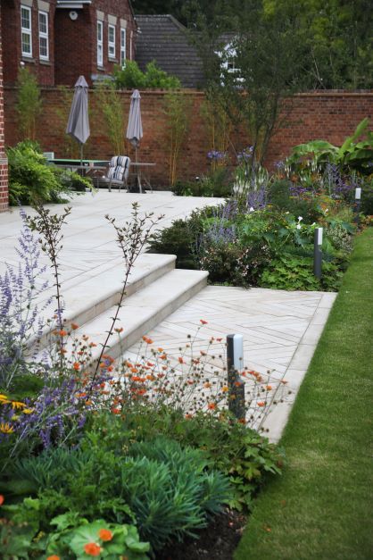 an outdoor garden with steps and flowers in the foreground, surrounded by brick buildings