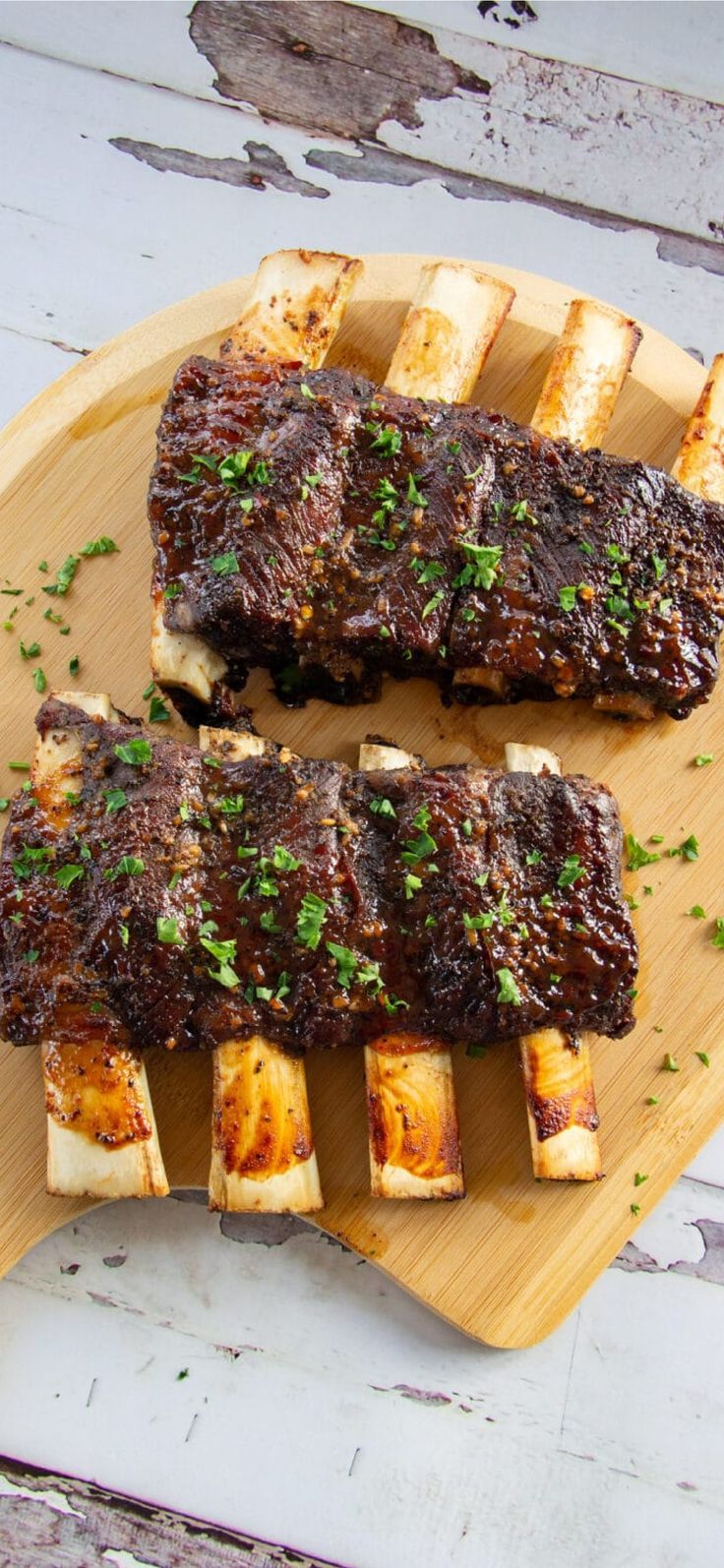 two pieces of meat sitting on top of a wooden cutting board next to some bread