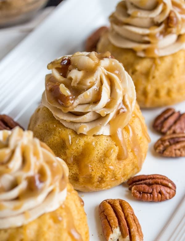 several desserts with pecans and icing sitting on a white plate next to each other