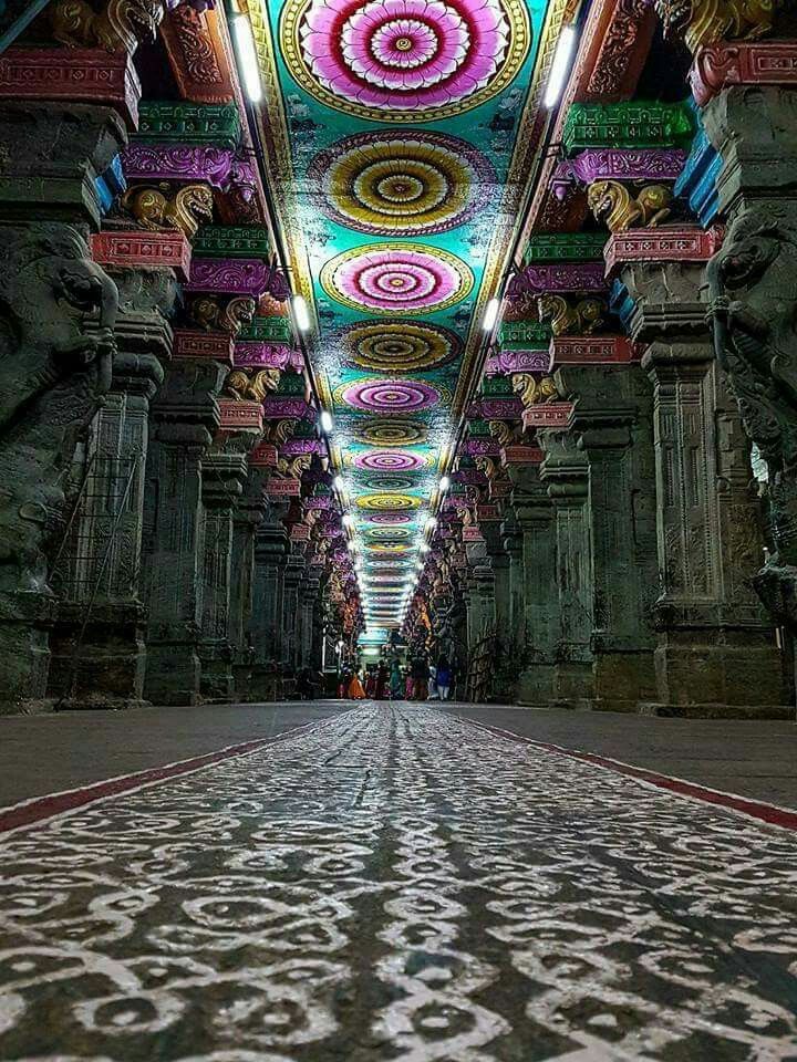 an intricately decorated walkway in the middle of a building with columns and ceiling lights