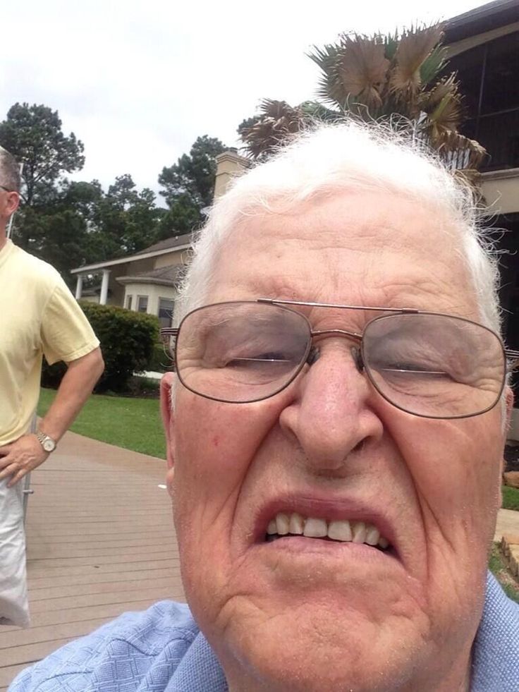 an older man wearing glasses and looking at the camera while standing in front of him