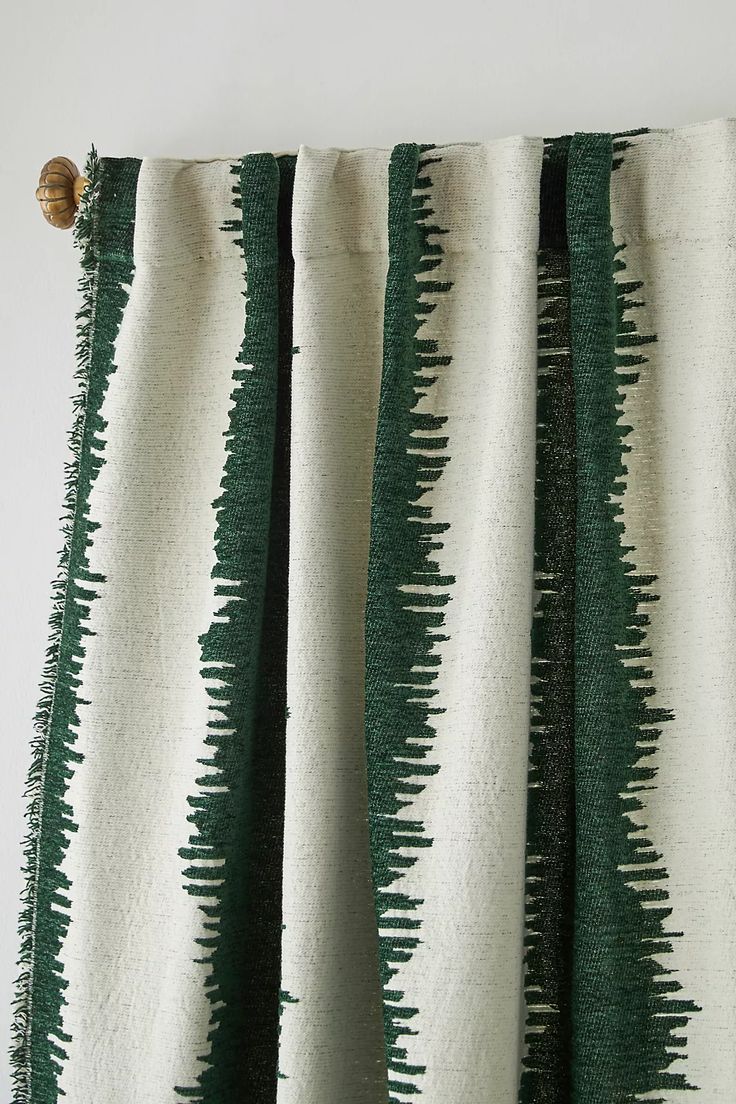 green and white striped curtains hanging on the side of a wall with a wooden button