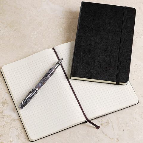 an open notebook with a pen sitting on top of it next to a notepad