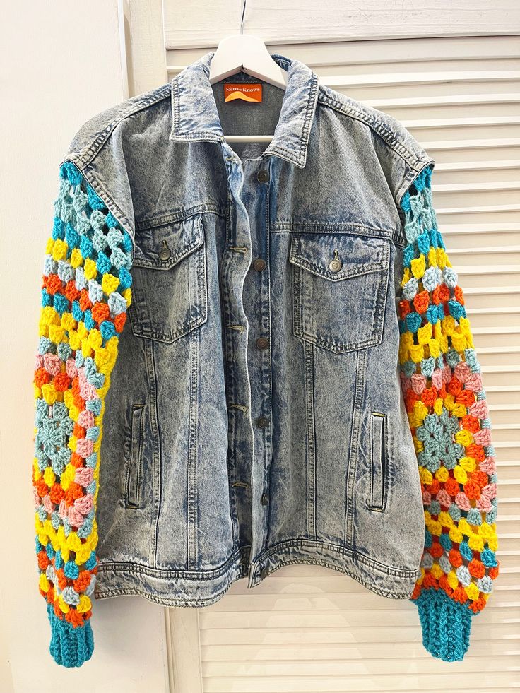 a denim jacket with crocheted sleeves hanging on a door