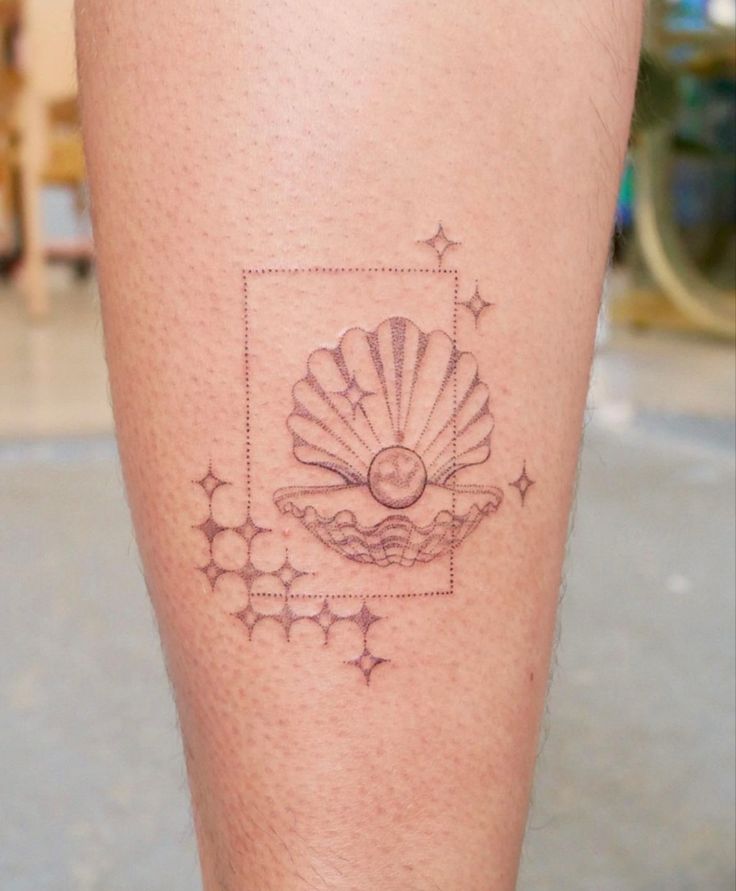 a person with a tattoo on their leg that has a shell and stars around it