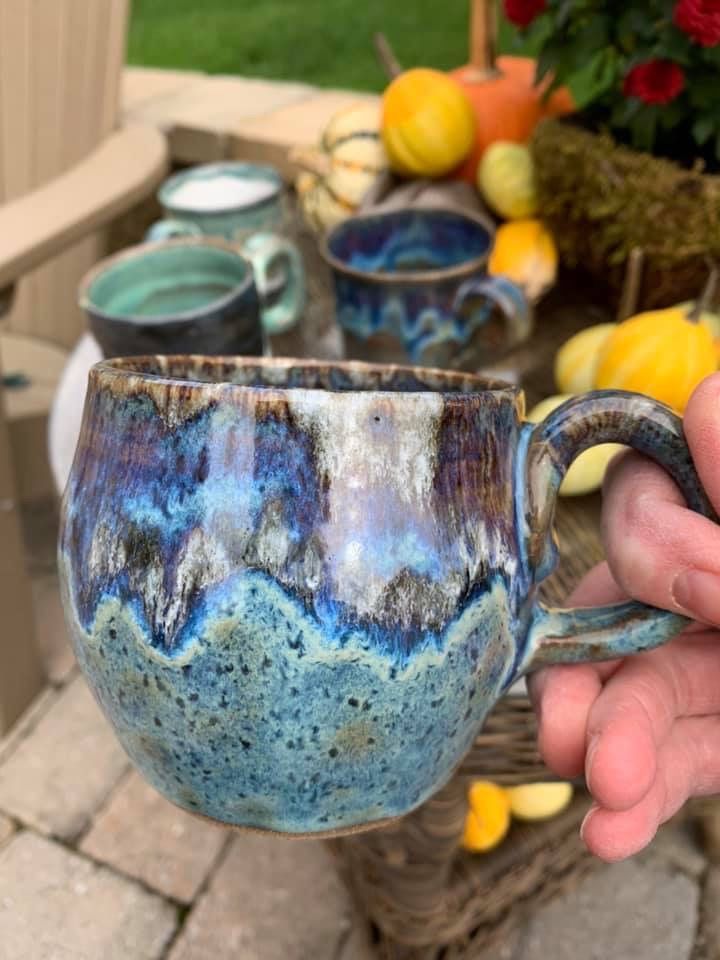 a hand holding a blue and white coffee cup