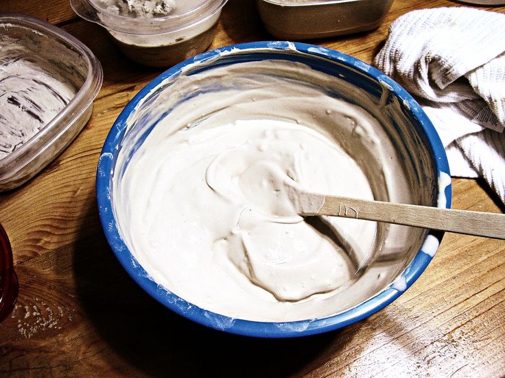 a blue bowl filled with cream sitting on top of a wooden table next to containers