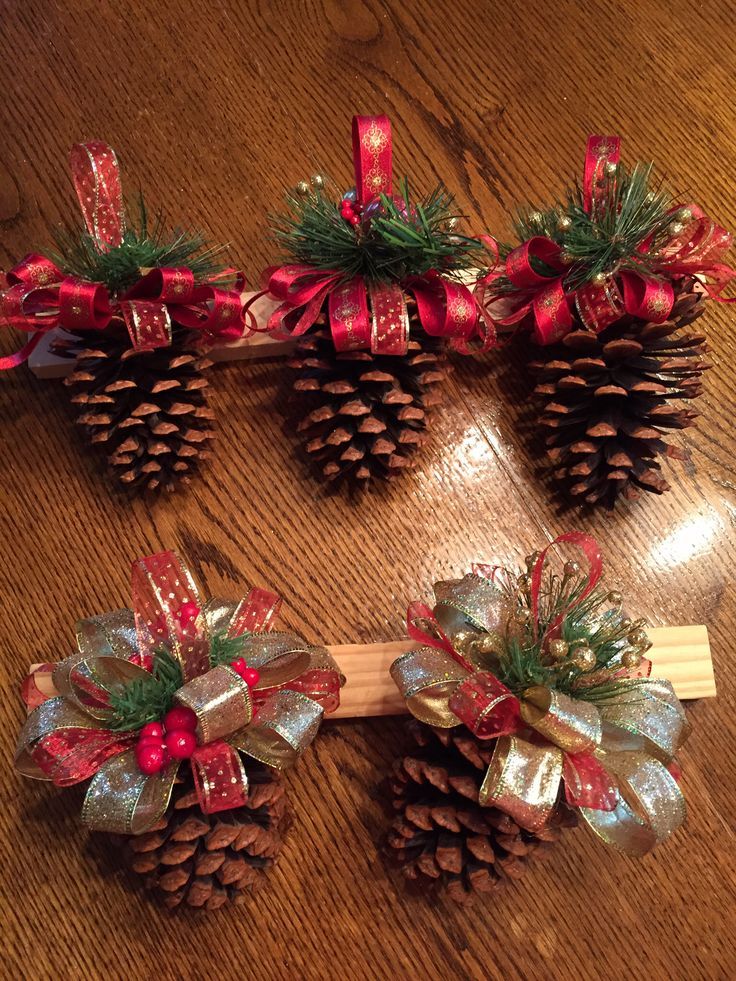 three pine cones with bows on them sitting on top of a wooden table next to a piece of wood