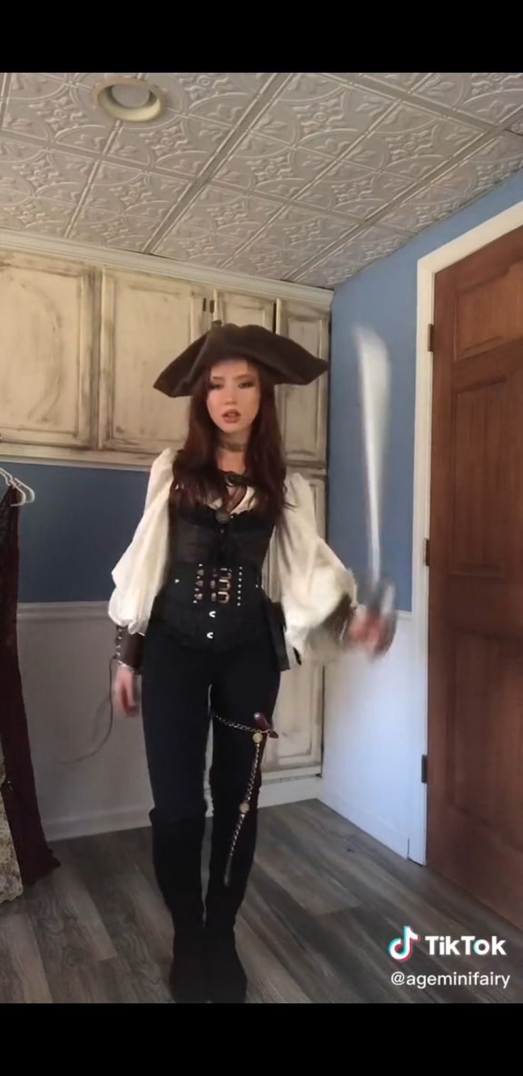 a woman dressed as a pirate holding two swords in her hand and wearing a hat