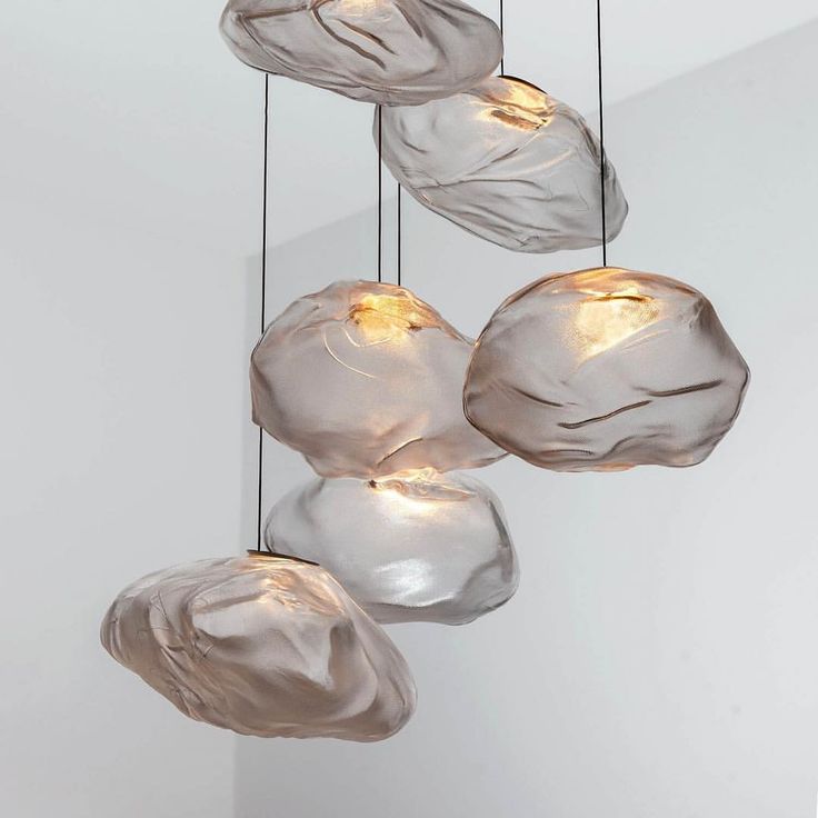 four glass lights hanging from the ceiling in a room with white walls and flooring