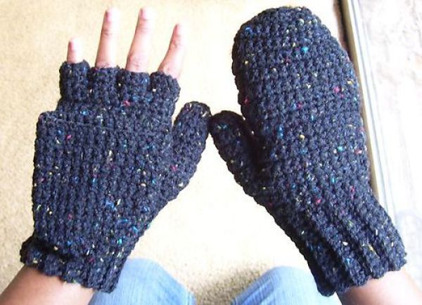 two blue knitted gloves sitting next to each other on top of a white surface