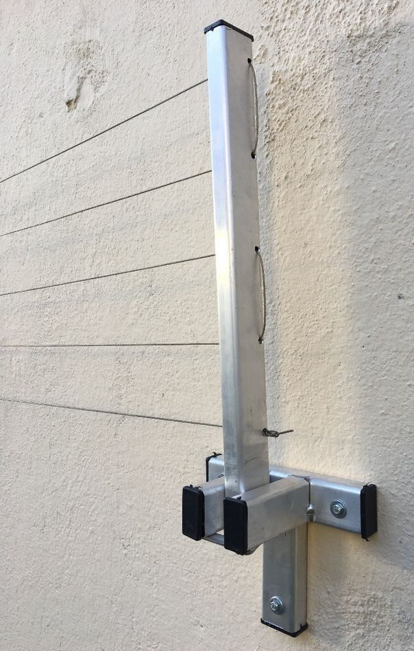 a metal pole mounted to the side of a building with two black brackets on it