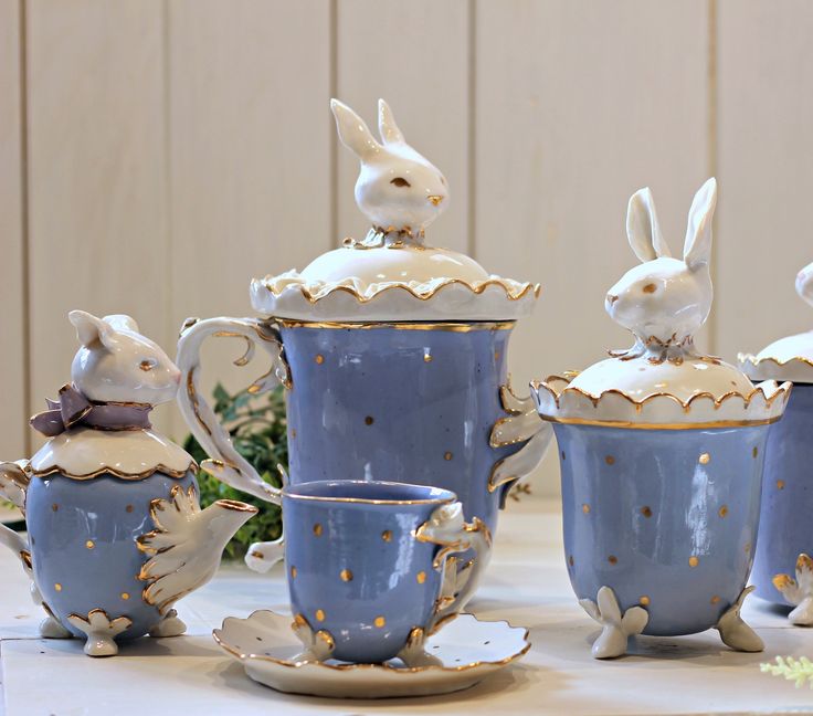 four tea cups with rabbits on them and one is holding a coffee cup in the middle