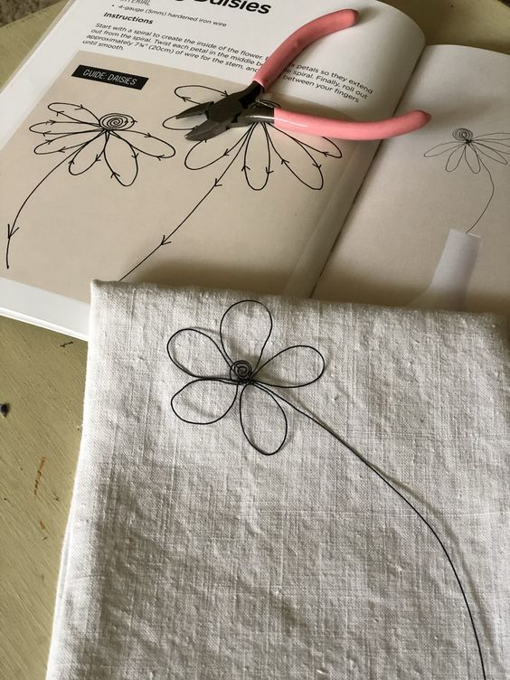 a pair of pink scissors sitting on top of a piece of cloth next to an open book