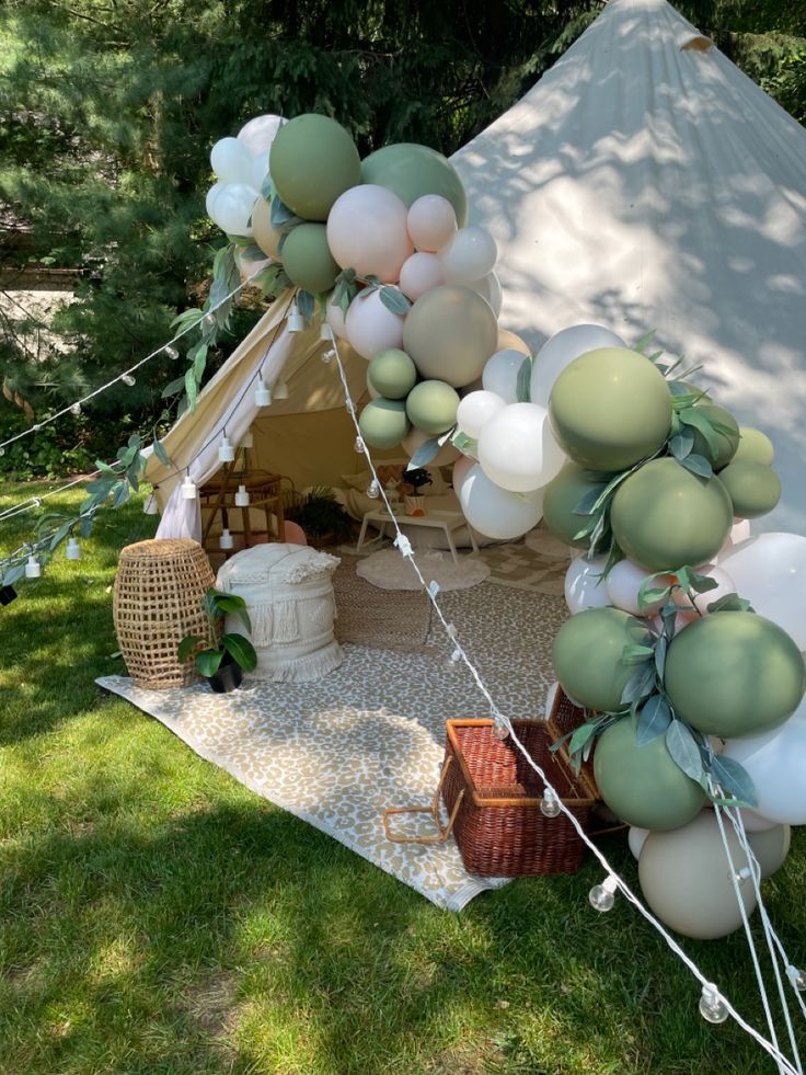 a tent is set up with balloons and greenery