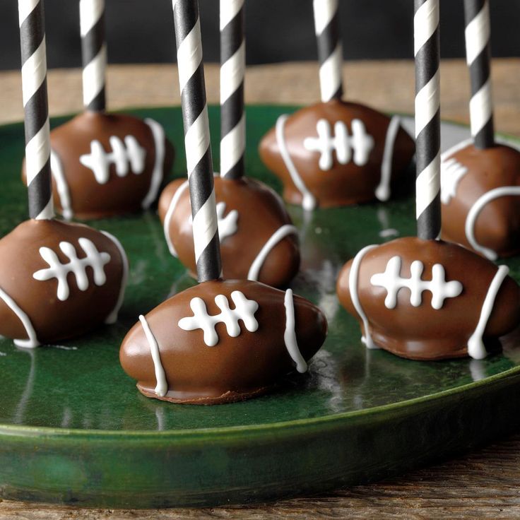 chocolate covered footballs with white and black striped candles on a green plate, ready to be eaten