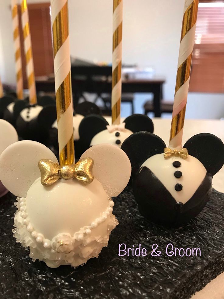 mickey mouse cake pops are decorated with gold and white frosting, topped with a bow