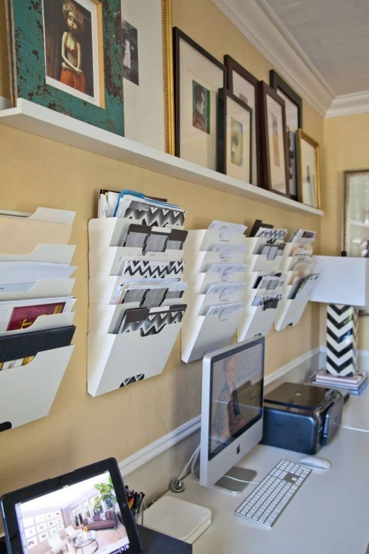 a desk with a computer, printer and pictures on the wall next to each other