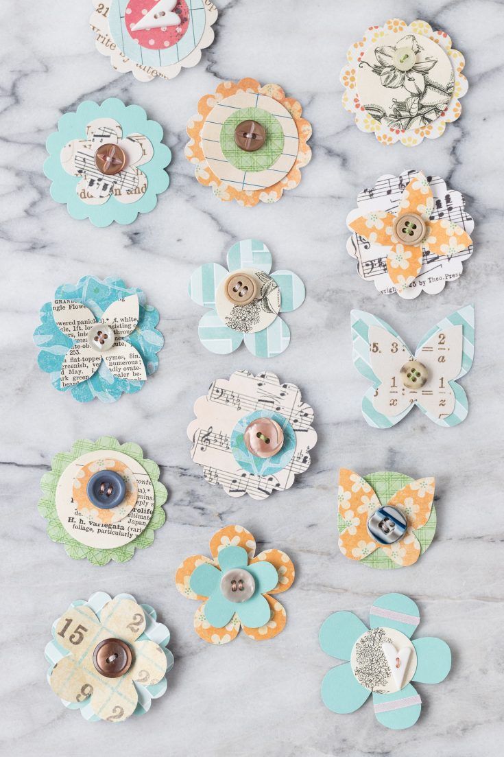 several different types of buttons on a marble surface with text overlay that reads, how to make paper flowers