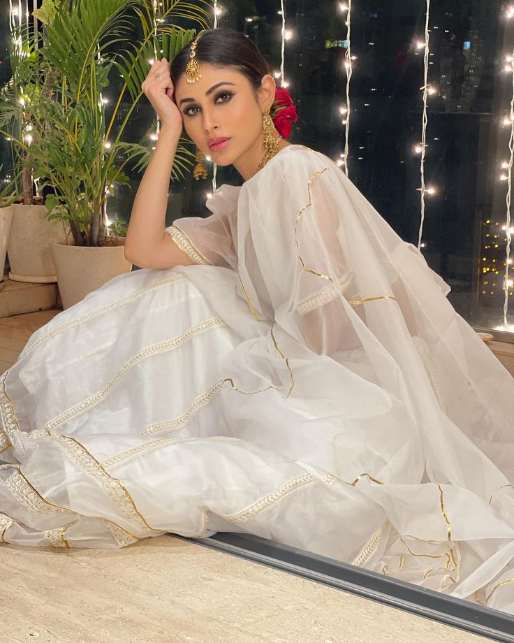 a woman sitting on the floor in a white dress