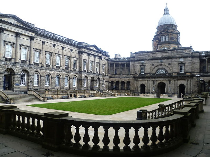 an old building with a green lawn in the middle and stairs leading up to it