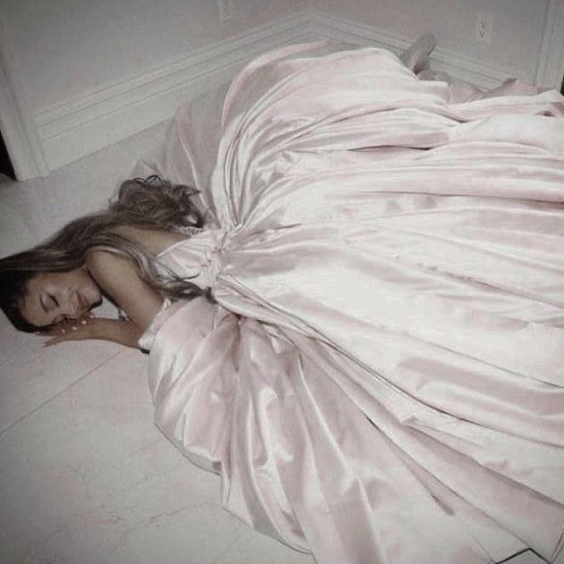 a woman in a wedding dress laying on the floor