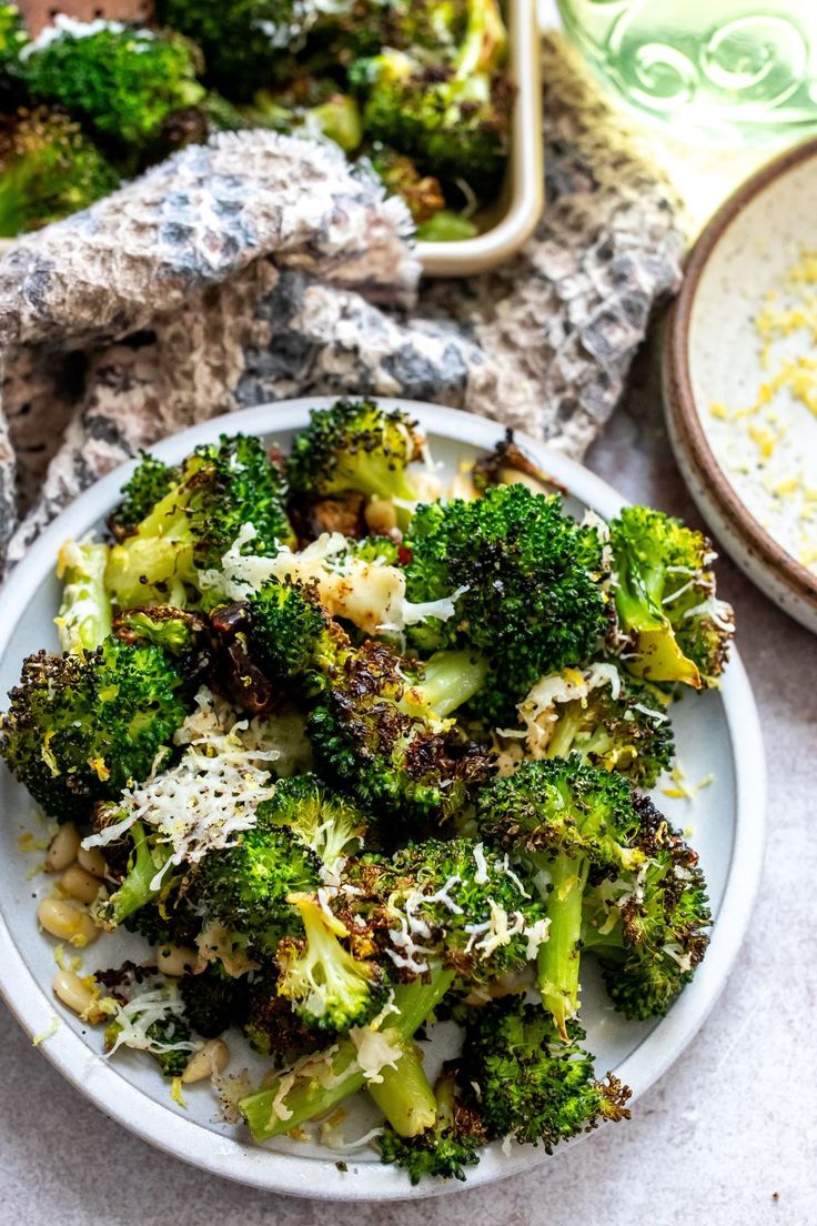 a white plate topped with broccoli covered in parmesan cheese