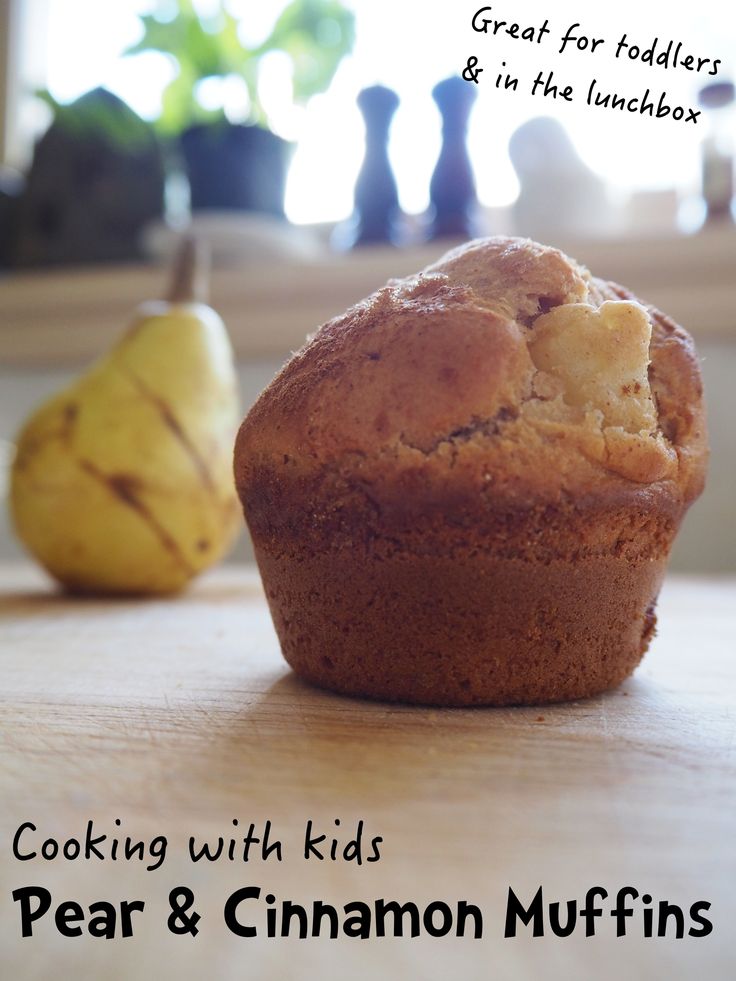 a muffin sitting on top of a wooden table next to two pears