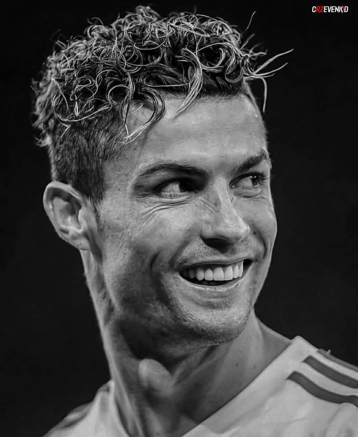 a black and white photo of a man with curly hair on his head smiling at the camera